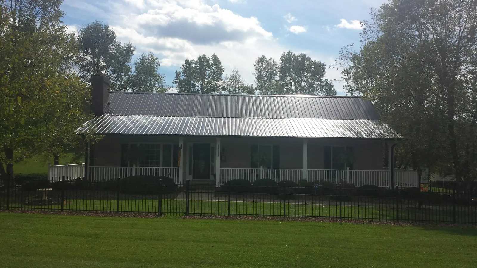 Gray metal roof on a brick ranch with a full width front porch — Gutter Guard Installation work by our crew in Van Hornesville