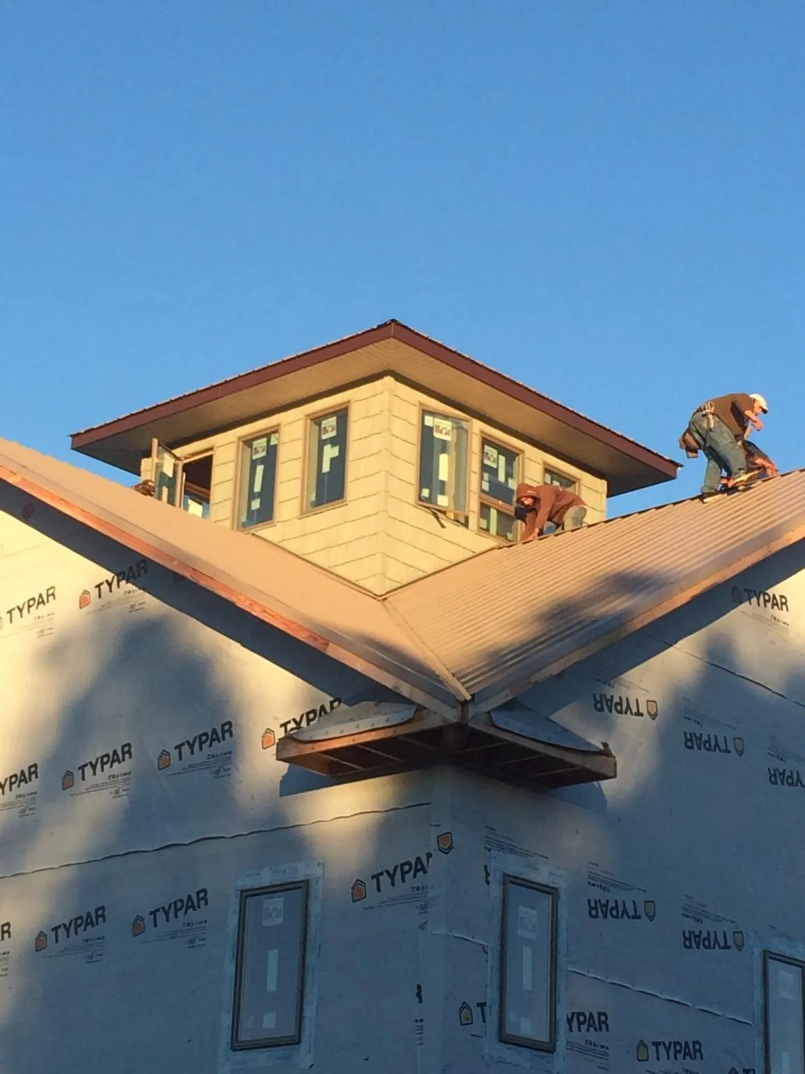 Roofers working around a rooftop cupola on a new metal roof at sunset — Roof Waterproofing in Van Hornesville by Roofing Brothers